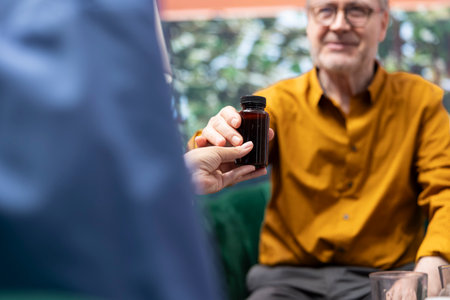 Social caretaker providing pills and medicine in different bottles for two patients, preparing the weekly treatment with daily doses for elderly man and woman. Nurse offer health aid. Close up.の写真素材
