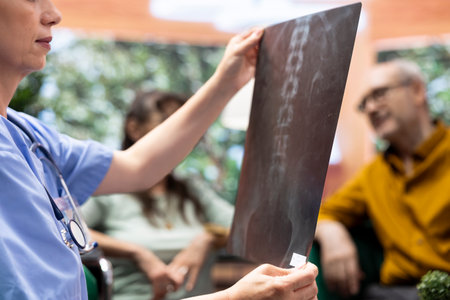 Nurse explaining the radiography result to senior patients to understand the diagnosis, elderly woman wheelchair user fighting for recovery. Medical assistant offering support during visit. Close up.の写真素材