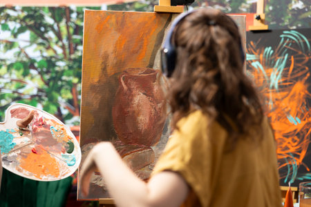 Diverse team of artists collaborating on a rustic colorful painting in art and craft workshop, mixing colors and applying them on a canvas. Two painters expressing their skill and creativity.の写真素材