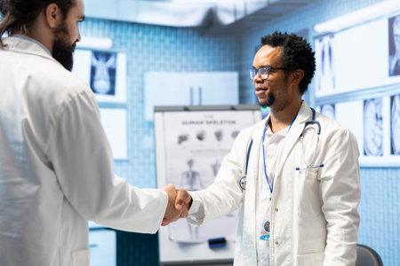 Diverse medics shaking hands after a successful treatment plan collaboration during a meeting with...