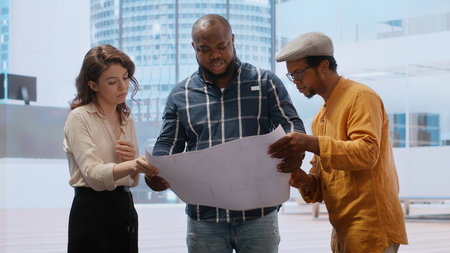 Client discussing with the real estate agent about architectural change and renovation, reviewing blueprints plans during office tour. Entrepreneur negotiating a leasing contract deal. Camera B.の写真素材