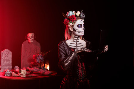 Woman working on laptop during Day of the Dead Mexican event honoring dead loved ones. Person...