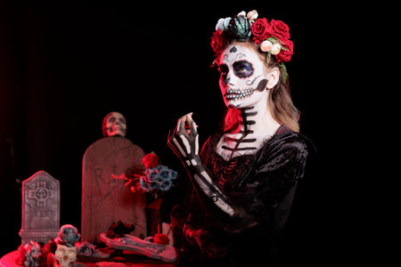 Woman wearing corpse makeup, horror costume and flower headband to celebrate dios de los muertos...
