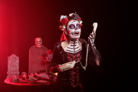 Dark lady talking on office cord telephone during Dia de los Muertos, preserving cultural...