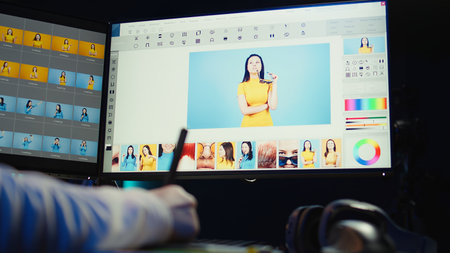 Photo editor using graphic tablet to retouch photographs with editing software on, zooming in to...