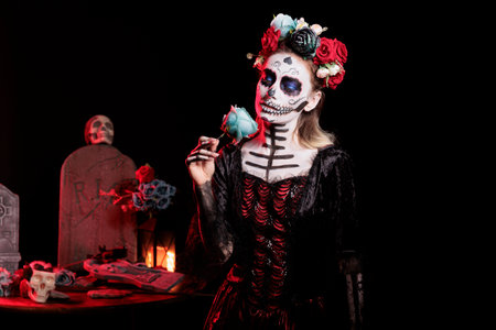 Girl smelling rose fragrance at Dia de los Muertos indigenous rites of honoring the dead. Woman...