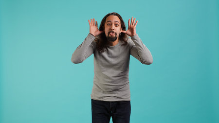 Portrait of man making exaggerated silly faces, mimicking someone, doing mocking gesturing. Person...