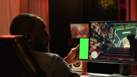 Isolated screen smartphone held by player competing in online multiplayer videogame at home. Mockup...