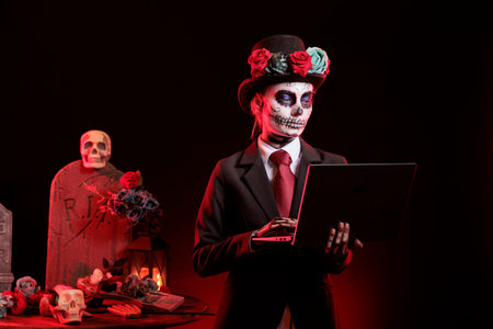 Lady working on laptop during Dia de los Muertos holiday. Woman types on notebook, wearing skeleton...