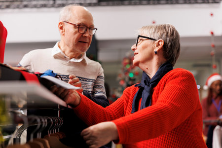 Old people looking at suit accessories in box before buying formal attire for christmas dinner event, holiday discount season. Two persons searching for ties from clearance section, shopping mall.の写真素材