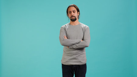 Man crossing arms, feeling upset by events, isolated over studio background. Portrait of stressed...