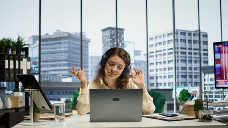 Business entrepreneur enjoys working with music on her headset, solving daily tasks at her corporate...
