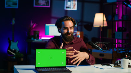 Entertainer presents chroma key laptop video, analyzing features. Content creator reviewing green screen notebook for technology enthusiasts, inspecting materials, camera Aの写真素材