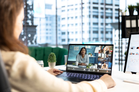 Determined female CEO leads a videoconference meeting with shareholders, encouraging open...
