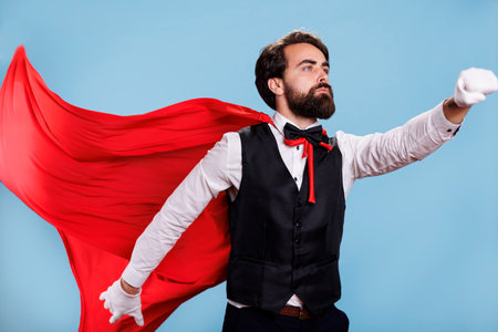 Strong character with fantasy cape standing with blue background, acting confident and determined on camera. Powerful person presenting dedication to protect citizens.の写真素材