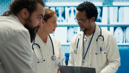Specialists discuss x ray results and patient care strategy in a medical office. Team of licensed doctors working together to provide accurate diagnosis and effective treatment plans. Camera A.の写真素材