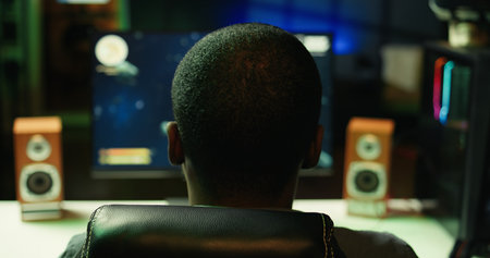 Gamer plays online multiplayer spaceship videogame with friends, relaxing in dark room. Player...