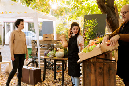 Family group of merchants arranging locally grown seasonal produce at harvest fair festival, getting...