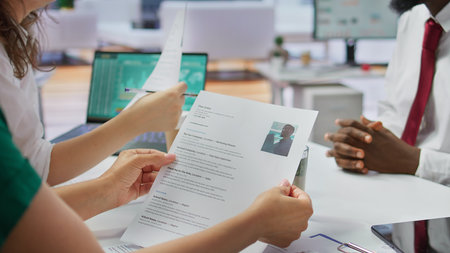 Job candidate hands over his CV to team of HR professionals in order to start interview, focusing on the experience in the resume. Discussing potential career development. Close up. Camera B.の写真素材