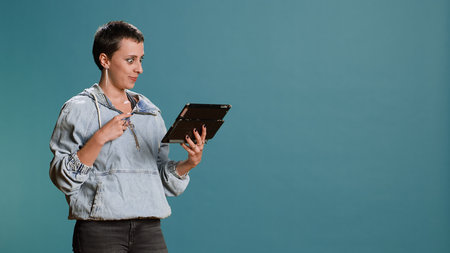 Stylish person doing online shopping with her credit card in studio, feeling happy spending money on...