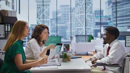 Wheelchair user job applicant giving his CV to the employers team, participating at interview for vacancy in corporation with inclusion and equality employment policy. Skilled candidate. Camera B.の写真素材