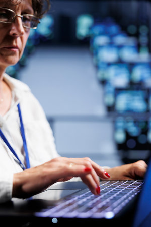 Skilled expert using laptop to make sure valuable data remains shielded from security issues,...
