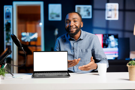 Influencer in home studio using recording tech to capture live broadcast, reviewing mockup laptop....