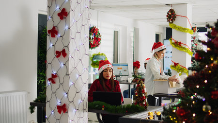 Trucking right shot of worker in festive decorated office packing desk belongings on last day at work. Staff member leaving job during year end before Christmas, saddening coworkersの写真素材