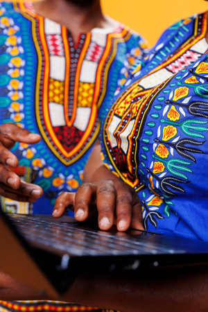 Black man and woman using laptop and scrolling internet page with touchpad closeup. African american couple holding fingers on portable computer close view while typing messageの写真素材