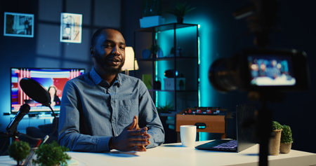 Smiling influencer in cozy home using professional camera to film live broadcast for online...