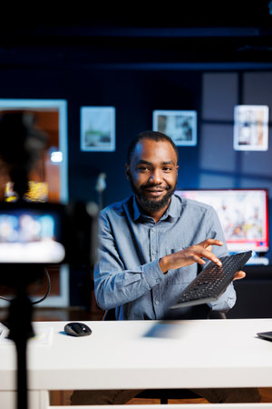 African american man filming tech tutorial on how to do replace keycaps on broken keyboard. Technology internet show host teaching subscribers how to mend computer peripheralの写真素材