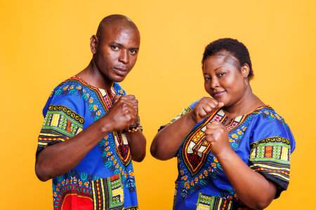 Smiling confident black man and woman posing with clenched fists portrait. Couple fighters standing...