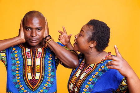 Black couple in relationship in fight having family dispute concept. Annoyed african american woman shouting while unhappy frustrated man closing ears with arms and looking at cameraの写真素材