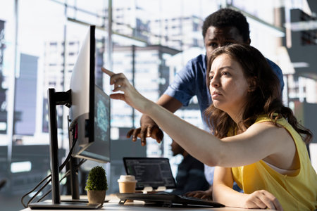 Supervisor asking accountant to show him business project tasks progress in modern office during nightshift. Management executive overseeing employee working on computerの写真素材