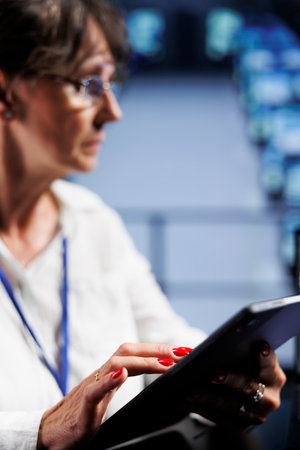 Close up of octogenarian engineer writing script code in data center on laptop terminal. Precise...