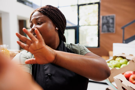 Young black woman with an apron promoting eco friendly bio products for sustainable living. African american storeowner creating content of environmentally conscious store for social media.の写真素材