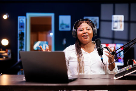 African american using professional recording equipment at home, filming channel intro for online streaming platforms. Female vlogger looking at camera and greeting her viewers.の写真素材