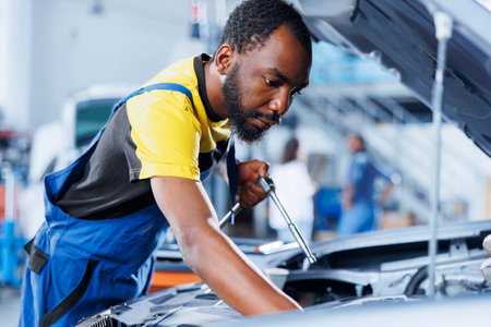 Mechanic in car service using professional mechanical tool to repair broken brakes. Competent worker in garage fixing client automobile, ensuring optimal automotive performanceの写真素材