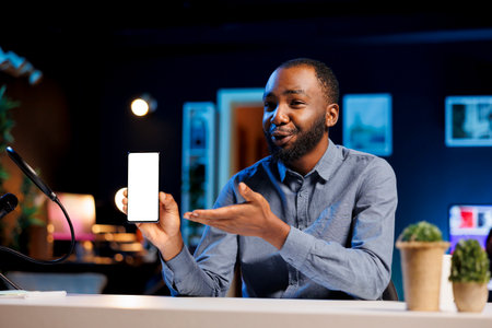 Influencer using high quality recording devices to shoot mockup smartphone review for vlog channel on online platforms. Internet star warmly welcoming dedicated viewers, filming isolated screen phoneの写真素材