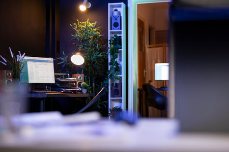 Living room is transformed into functional workspace, complete with a pc, desk, chair, and laptop. Interior design seamlessly blends the work and home environment for comfortable remote work setting.の写真素材