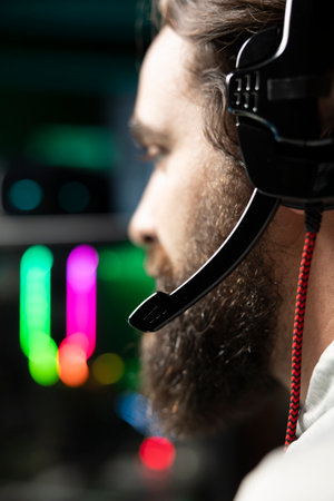 Content creator playing videogames live while chatting with internet audience from RGB lit studio. Close up of gamer streaming multiplayer game while discussing his strategies with fansの写真素材