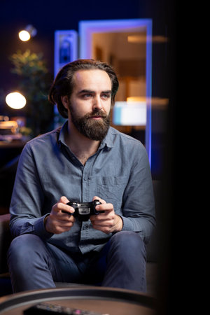 Man playing shooter videogame in neon lit room, holding controller. Gamer participating in internet...