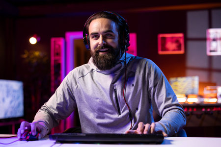 Happy pro gamer in studio teaching subscribers strategies to beat foes during livestream. Jolly man...
