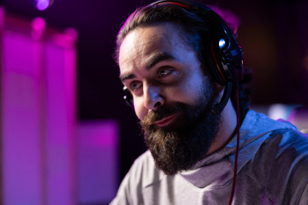 Pro gamer at home chatting with internet teammates using headphones mic, competing together in...