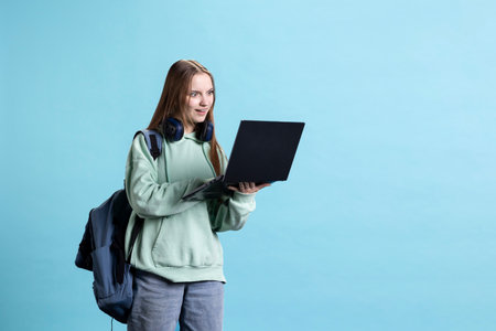 Upbeat teenager opening laptop, excited to start job shift, isolated over studio background. Portrait of radiant girl with notebook ready to do business related tasks on itの写真素材