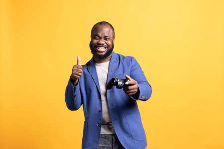 Cheerful gamer showing thumbs up sign gesturing holding controller, happily playing videogames....