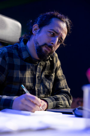 Detailed view of male blogger writing on his notebook, reviewing and planning content for his blog....