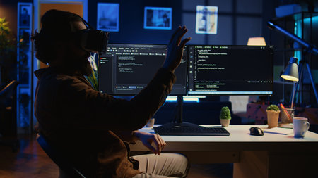 Teleworking programmer using futuristic VR glasses in home office to do javascript programming. IT expert wearing high tech virtual reality headset to visualize lines of code, camera Bの写真素材