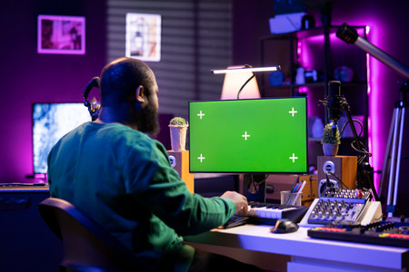 Songwriter operates on synthesizer piano keys next to isolated display, composing new music with...