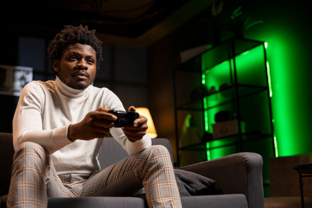 Man playing singleplayer videogame on gaming console, feeling turned off by levels. Player disappointed by game, struggling to maintain interest, using gamepad controllerの写真素材